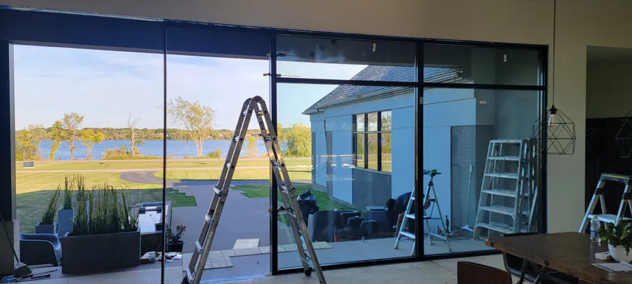 Floor-to-ceiling sliding glass wall facing the water, during installation